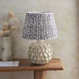 Ashbury Leaf Table Lamp in grey, ceramic disc-textured base with pleated leaf-patterned shade, shown on a wooden console table.