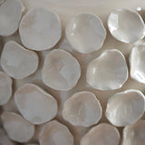 Close-up of the Ashbury table lamp's ceramic base, showing sculptured petal-like forms in an ivory crackle glaze finish.