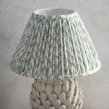 Endon Caldford table lamp with pleated green and white leaf-print fabric shade above an ivory crackle-glazed ceramic base with layered leaf details.
