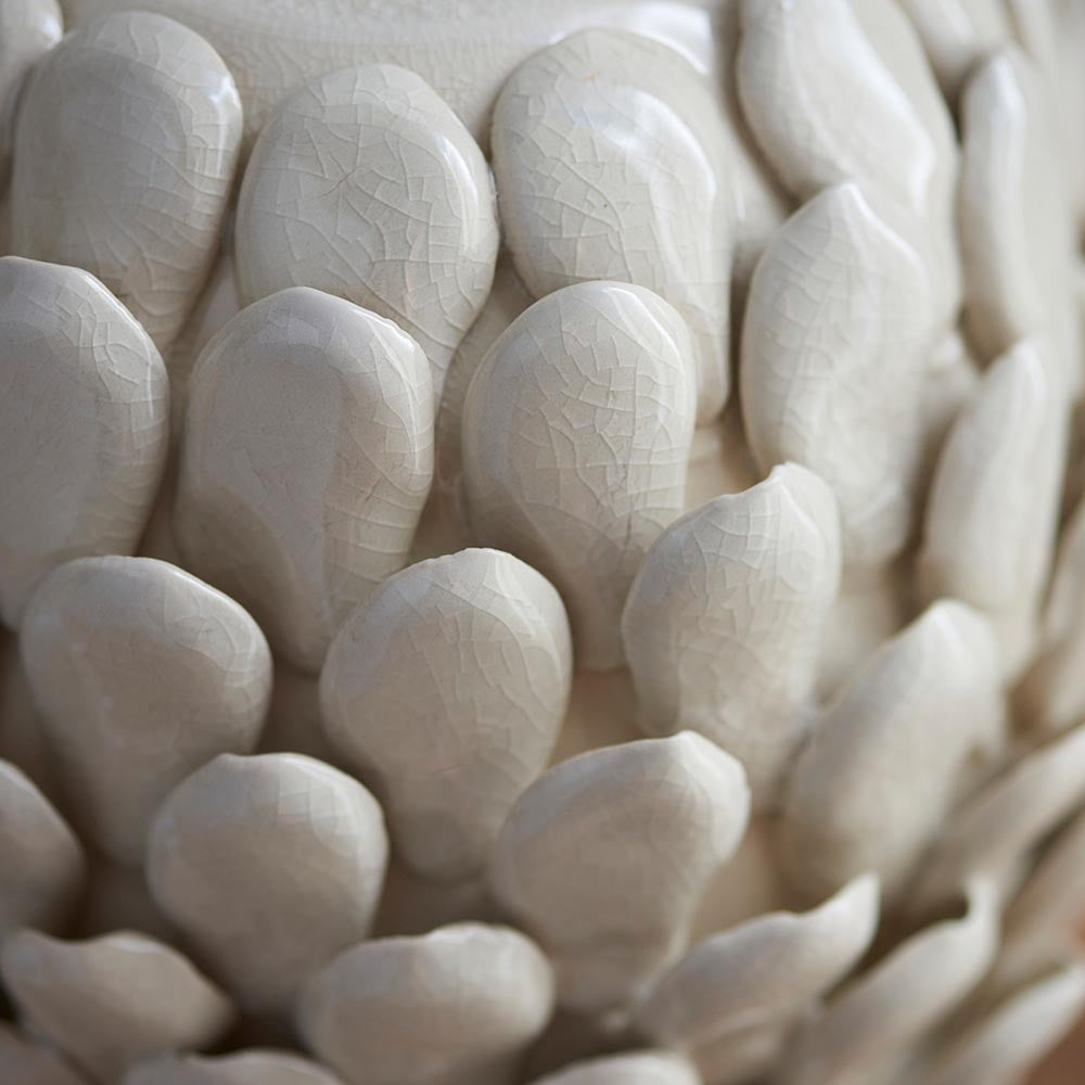 Close-up of the Caldford table lamp base, showing ivory crackle-glazed ceramic with handmade, overlapping leaf-shaped details.