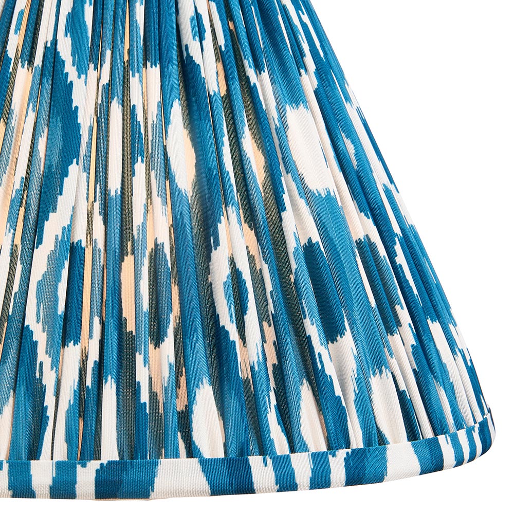 Close-up of the Caldford Table Lamp's pleated 30cm Ikat shade in blue, cream and natural faux silk with brass trim edging.