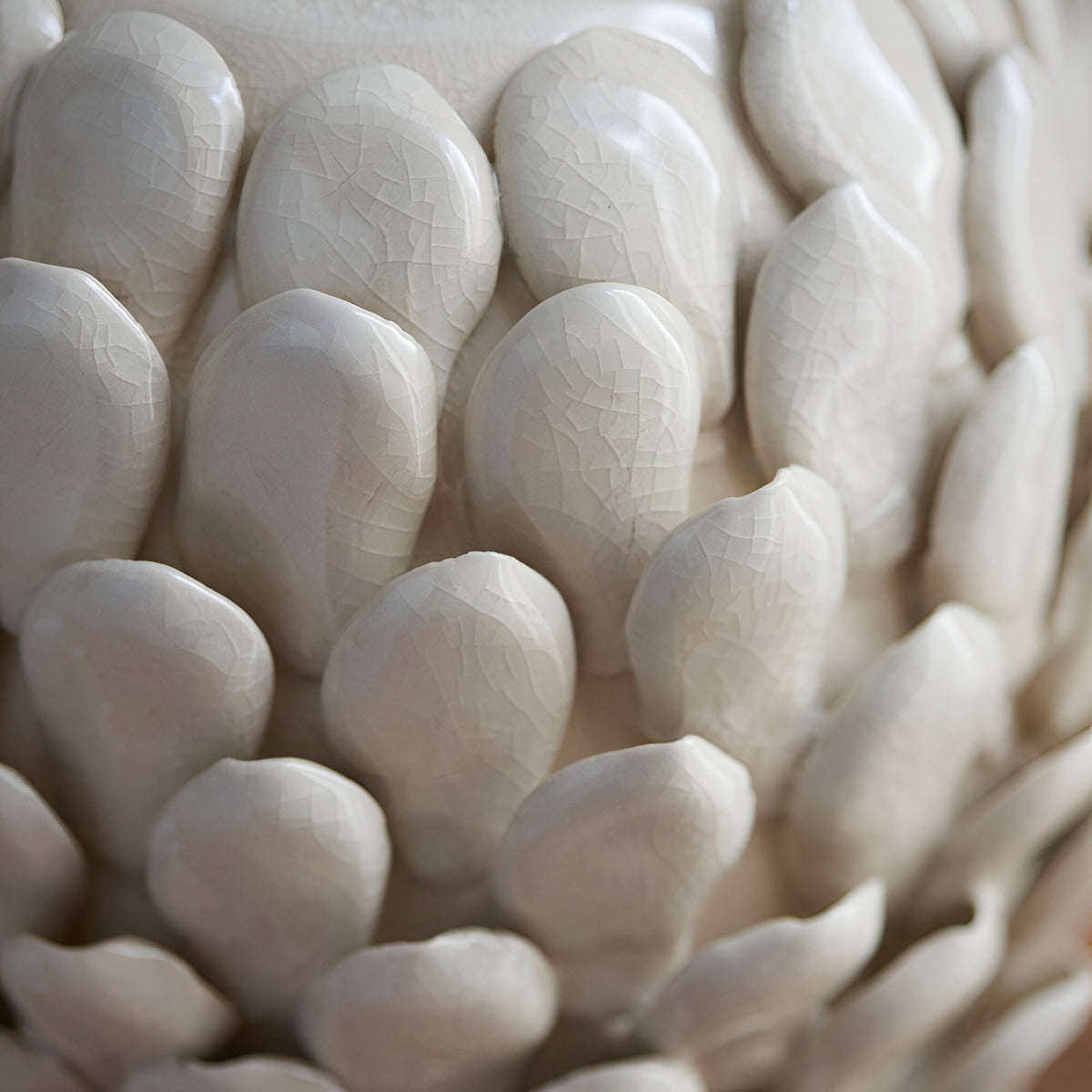Close-up of the Endon Caldford table lamp's ivory crackle-glazed ceramic base, showing handmade leaf-shaped details in a layered, petal-like arrangement.