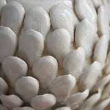 Close-up of the Endon Caldford table lamp's ivory crackle-glazed ceramic base, showing handmade leaf-shaped details in a layered, petal-like arrangement.
