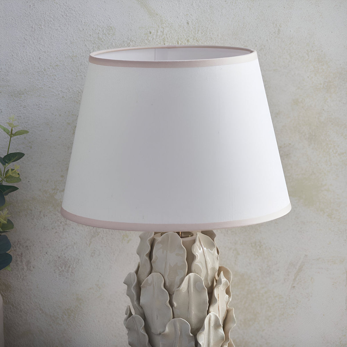 Caldford Ivy 35cm table lamp with ivory crackle-glazed ceramic leaf-detail base and white tapered fabric shade with pink trim.
