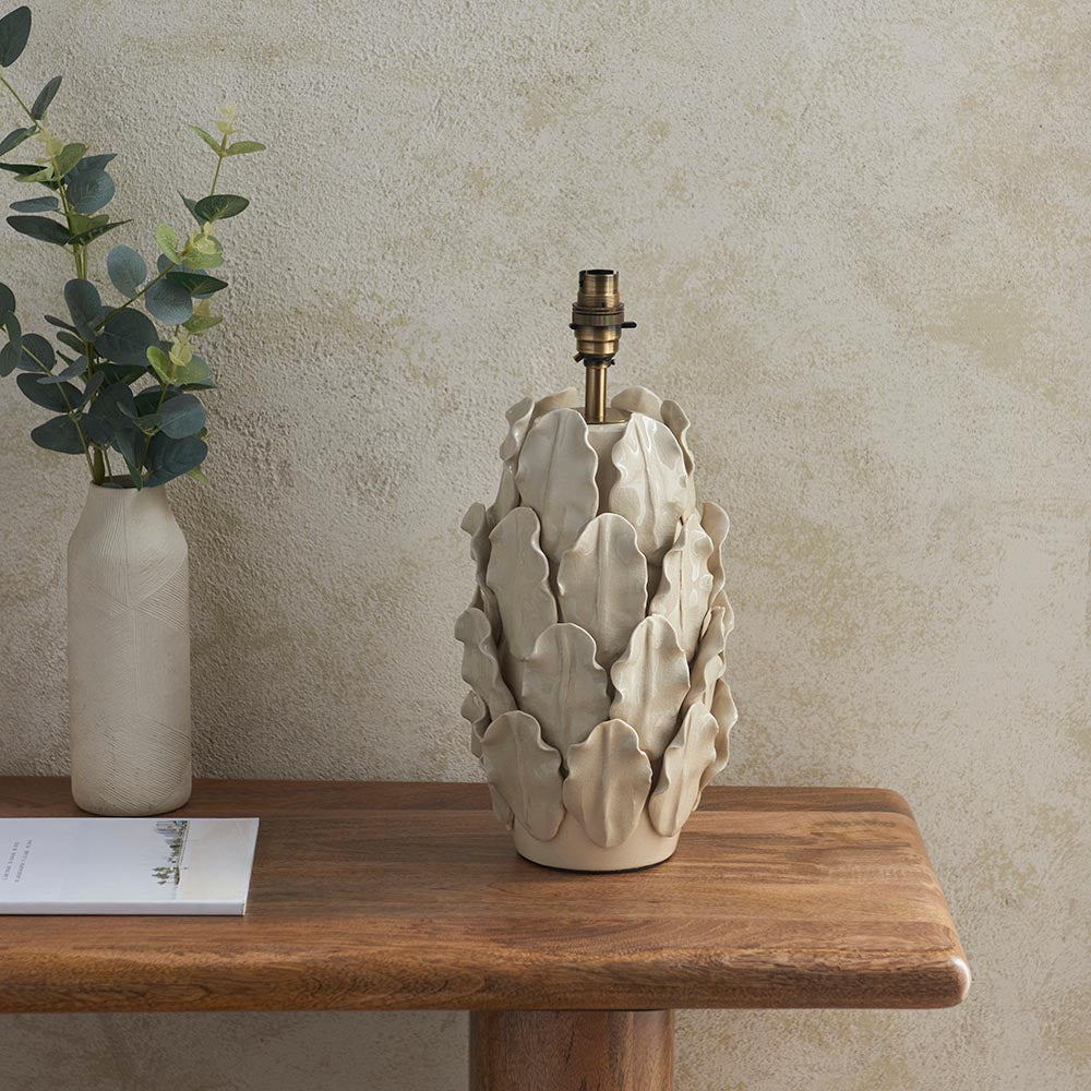 Endon Caldford ceramic table lamp base with sculpted leaf detailing in ivory crackle glaze and brushed brass B22 holder, on a wooden console beside a vase.