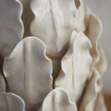 Close-up of the Endon Caldford table lamp's handmade ceramic base, showing sculpted palm and fern leaf details in an ivory crackle glaze.
