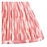 Close-up of the Carlstead Table Lamp's pleated Ikat shade in pink and white patterned fabric with a gathered finish and trimmed edge.