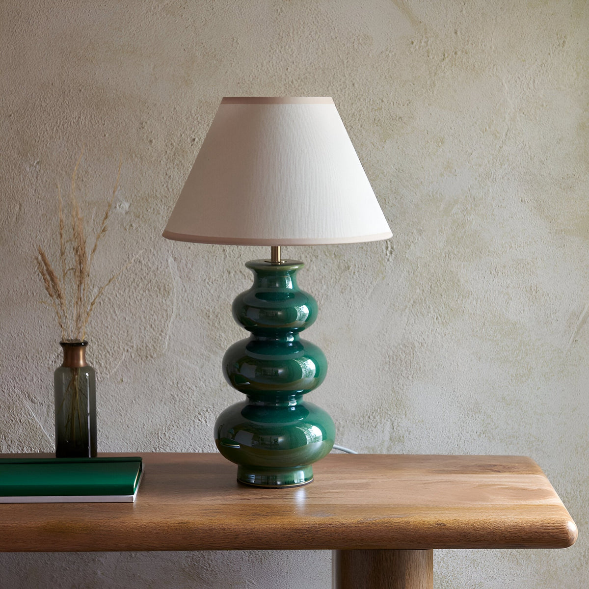 Carlstead Ivy Table Lamp with glossy green ceramic gourd-shaped base and ivory fabric shade, shown on a wooden console table.