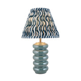 Cliffstead Table Lamp featuring a ribbed ceramic base in blue reactive glaze, brass fittings, and a pleated blue-and-white patterned fabric shade.