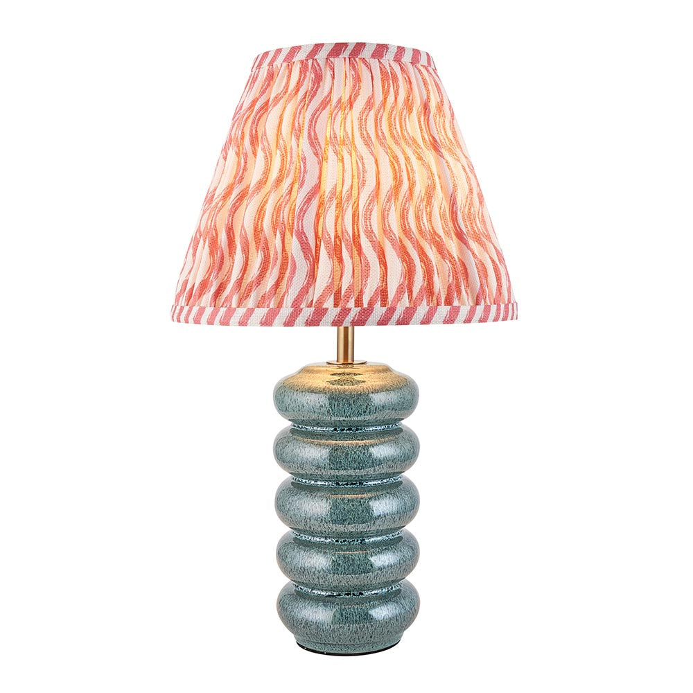 Cliffstead table lamp with ribbed silver-blue ceramic base, brass fitting, and pink wave-patterned tapered fabric shade, shown on a white background.
