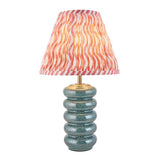 Cliffstead table lamp with ribbed silver-blue ceramic base, brass fitting, and pink wave-patterned tapered fabric shade, shown on a white background.