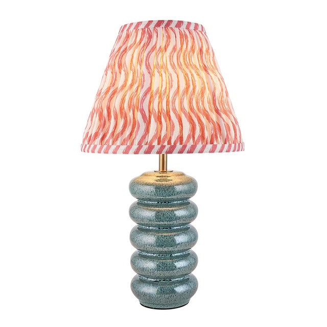 Cliffstead table lamp with ribbed silver-blue ceramic base, brass fitting, and pink wave-patterned tapered fabric shade, shown on a white background.
