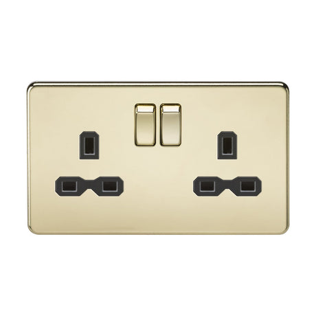 The 13A 2 Gang DP Switched Socket with Twin Earths, featuring a polished brass finish and a black insert in a screwless low profile design, includes two switches and three-pin plug inputs. Its gold-colored, sleek surface beautifully reflects light, enhancing its polished appearance.