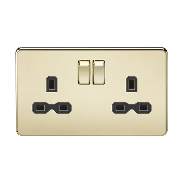 The 13A 2 Gang DP Switched Socket with Twin Earths, featuring a polished brass finish and a black insert in a screwless low profile design, includes two switches and three-pin plug inputs. Its gold-colored, sleek surface beautifully reflects light, enhancing its polished appearance.