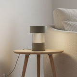 Balise Cylinder Ribbed Glass Lantern Table Lamp in green, with fluted glass midsection and iron top and base, shown lit on a side table beside a sofa.