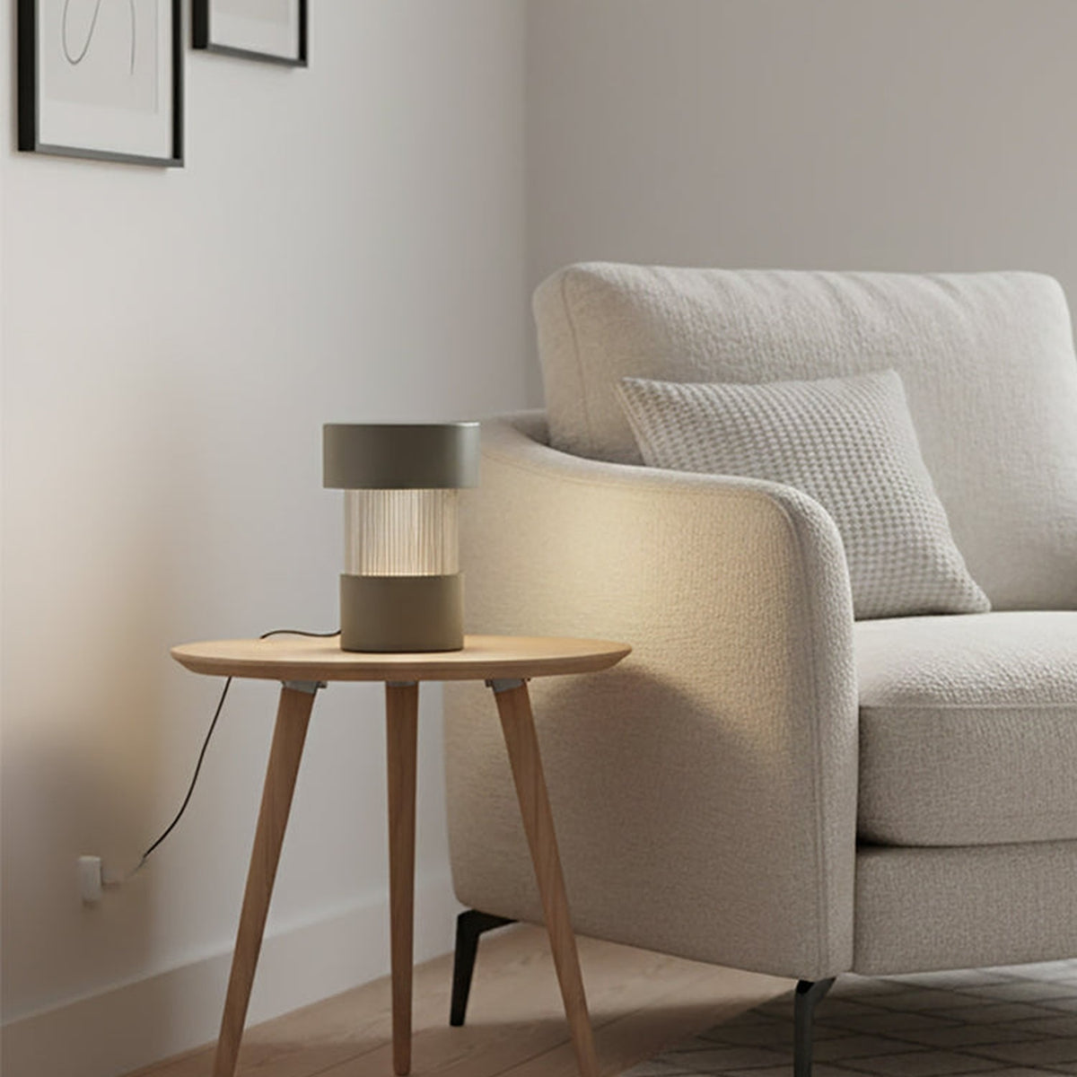 Balise Cylinder Ribbed Glass Lantern Table Lamp in green, lit on a wooden side table beside a cream sofa in a living room setting.