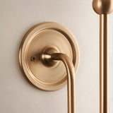 Close-up of the Cliffleigh Leaf Wall Light's brushed brass wall backplate and curved arm with visible fixing screw, shown without the fabric shade.