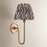 Cliffleigh Ikat Wall Light in antique brass with a pleated grey and white patterned tapered fabric shade, on a plain light background.