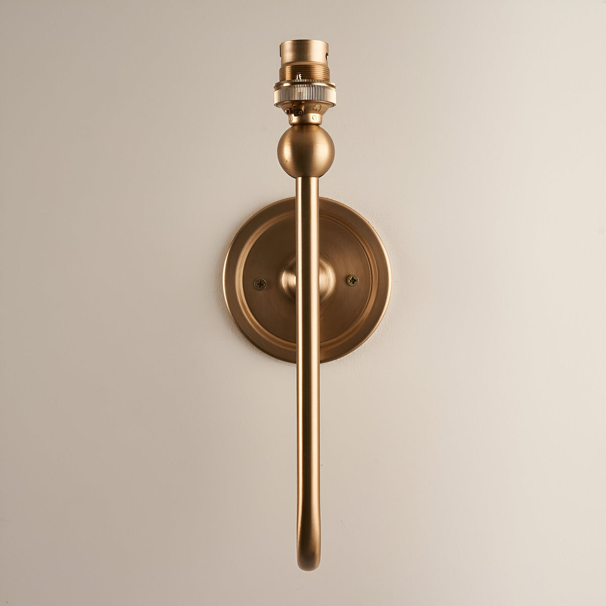 Cliffleigh Wall Light in Ivy shown without shade, featuring a round backplate, slim upright brass arm and B22 lamp holder on a plain light background.