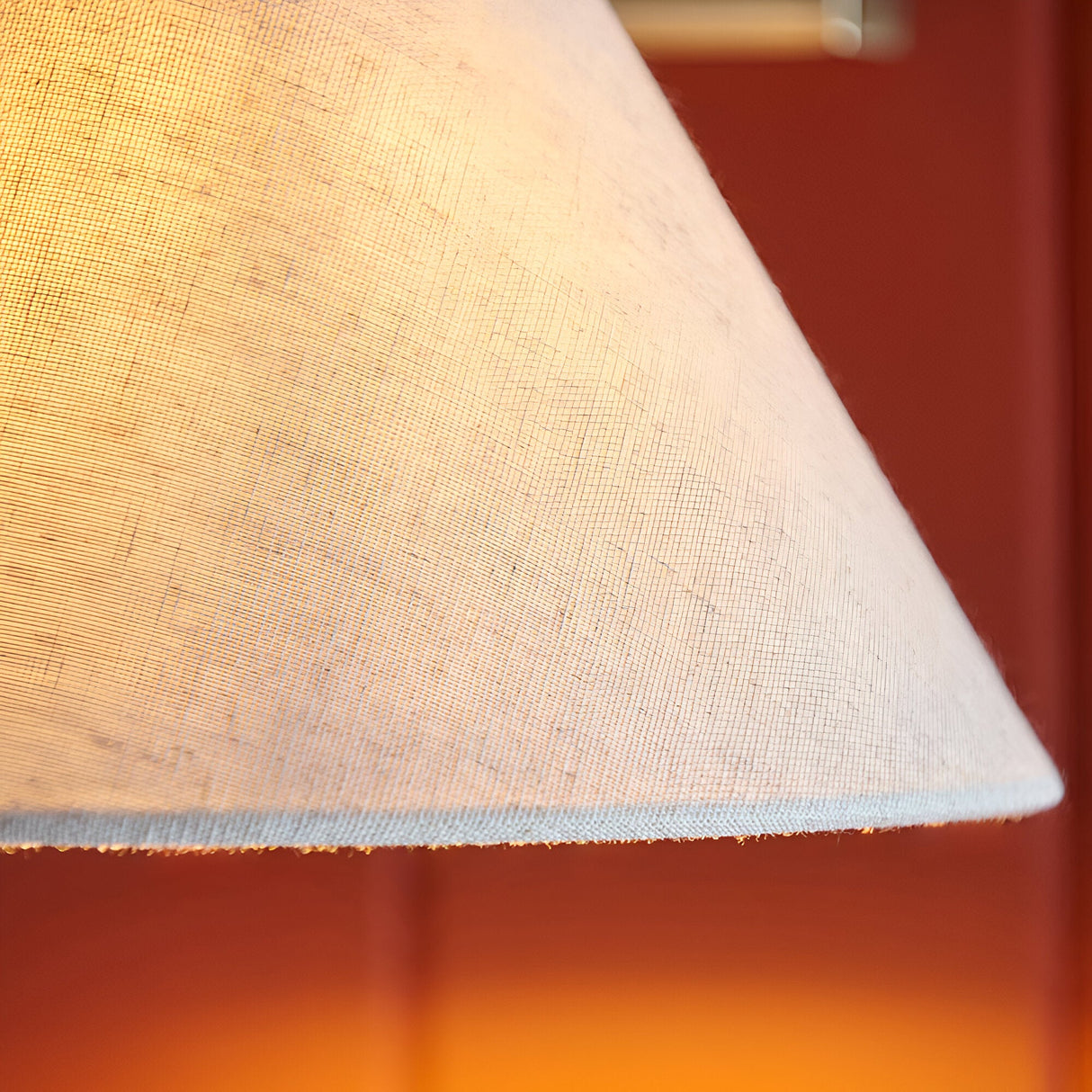 Close-up of the Brockwood Wall Light's tapered natural linen shade, showing textured fabric and stitched edge against a warm brass glow.