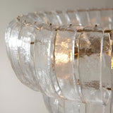 Close-up of the Carlwell 6 Light Pendant, showing curved textured glass panels tiered around a brushed antique brass frame.