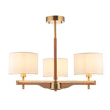 Bramwell 3-light semi-flush ceiling light with aged brass frame, oak arms and cream linen drum shades, on a plain white background.