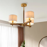 Bramwell 3-light semi-flush ceiling light with aged brass frame, oak arms and linen drum shades, shown fitted in a room with sheer curtains.