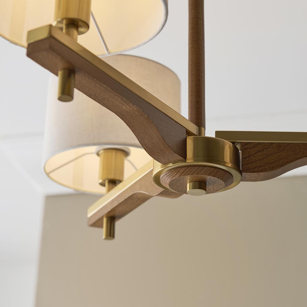 Close-up of the Bramwell 3 Light Oak & Linen Semi-Flush Ceiling Light, showing aged brass fittings and oak arms with linen shades against a plain background.
