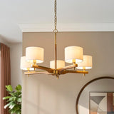 Bramwell 5 Light Pendant in brass and natural, with wood arms and fabric cylinder shades on a chain drop, shown above a dining table setting.