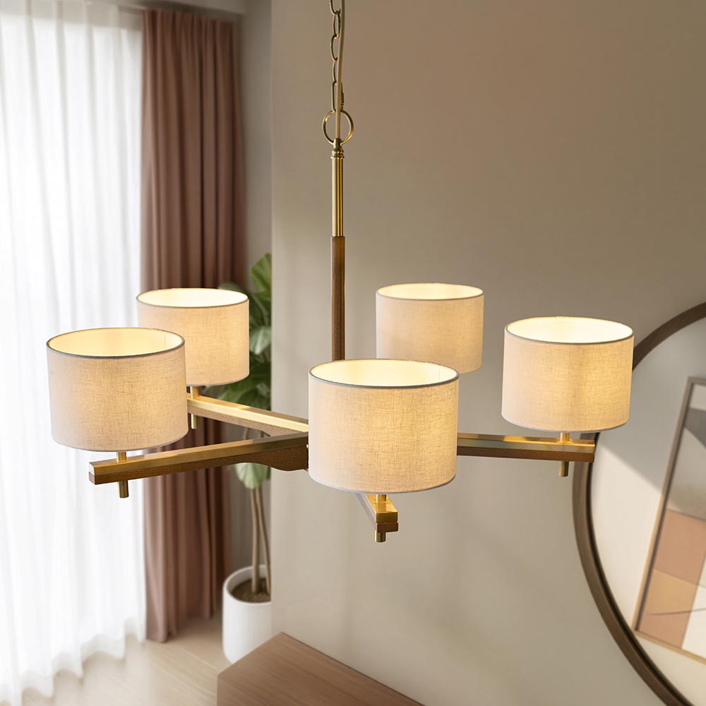Bramwell 5 Light Pendant with brass and wood frame, five natural linen cylinder shades and chain suspension, shown above a table in a living space.
