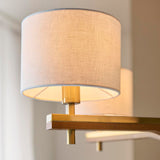 Close-up of the Bramwell 5 Light Pendant showing a natural linen cylinder shade with brushed brass fitting and wood-accented frame detail.