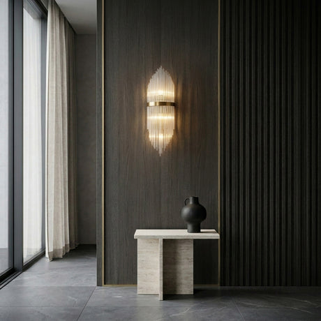 A modern interior with dark vertical wall paneling, luxury lighting from the Oriana 2 Light Crystal Wall Light in gold, a minimalist light stone bench, a black ceramic vase, and floor-to-ceiling windows with light curtains on the left.