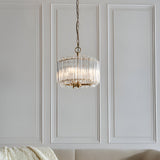 Endon Danebury 3 light pendant in brushed brass with tiered clear glass rods, suspended from a chain against a white panelled wall in a living room.