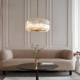 Endon Danebury 5 light pendant in aged brass with clear cut crystal rods on a chain suspension, above a coffee table and cream sofa in a panelled lounge.