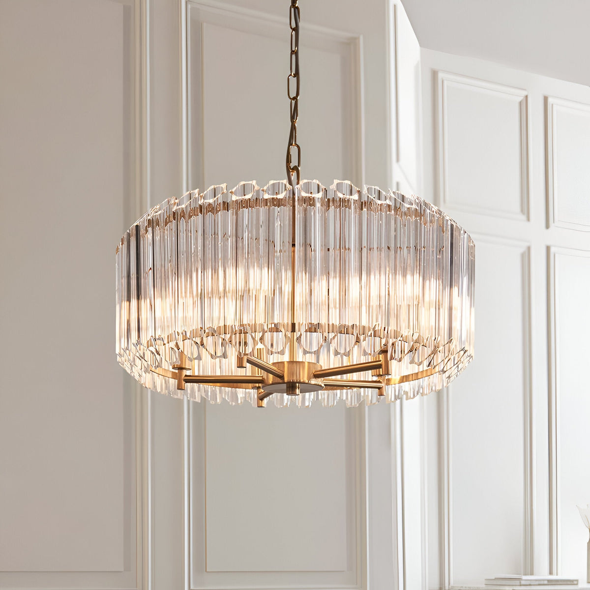 Endon Danebury 5 light pendant in aged brass with vertical clear crystal rods forming a drum shade, suspended from a chain against panelled walls.