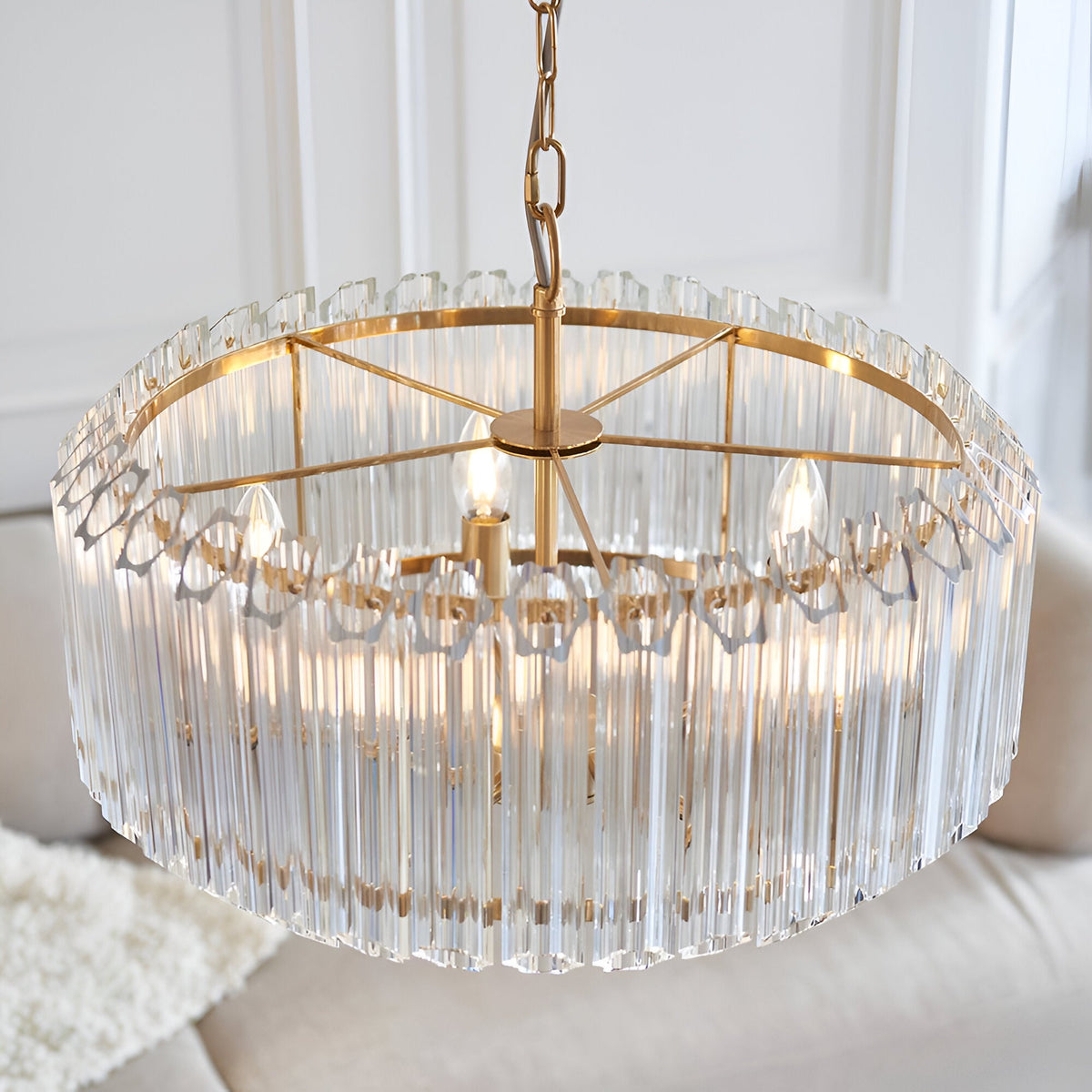 Endon Danebury 5 light pendant in brushed aged brass with vertical clear crystal rods, suspended from a chain in a bright living space.