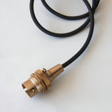Endon Brackmont Flex Set pendant with brushed aged brass B22 lampholder and coiled black braided fabric cable on a plain white background.