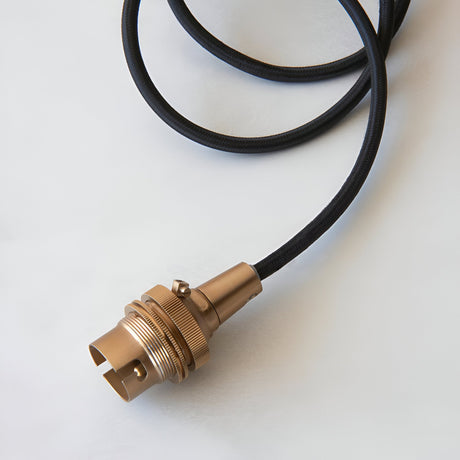 Endon Brackmont Flex Set pendant with brushed aged brass B22 lampholder and coiled black braided fabric cable on a plain white background.