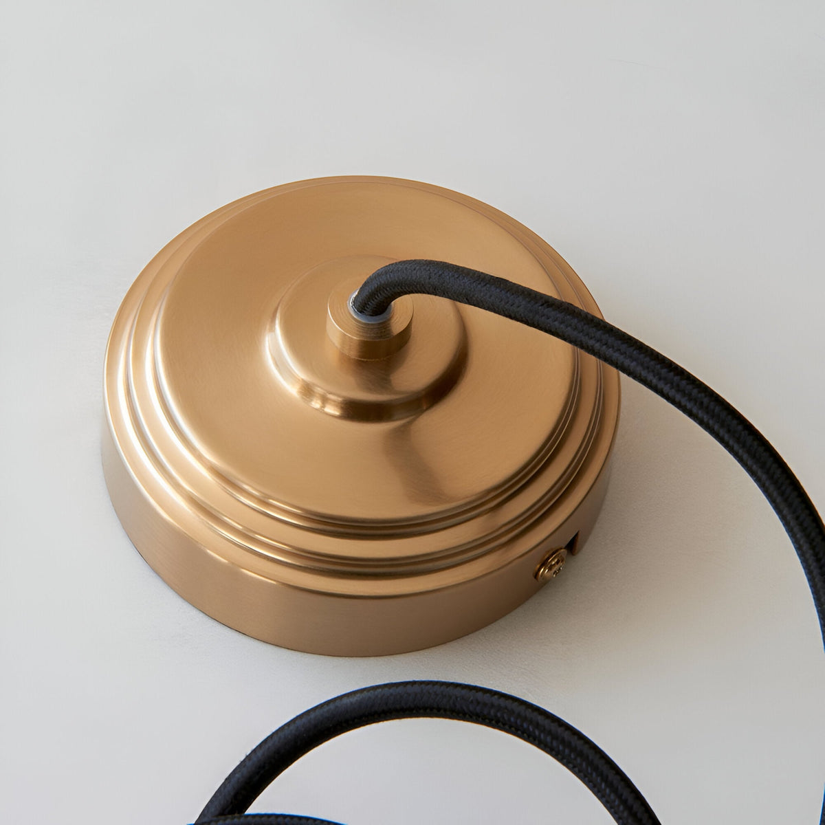 Endon Brackmont Flex Set pendant ceiling rose in brushed aged brass with black braided fabric cable, shown on a plain white background.