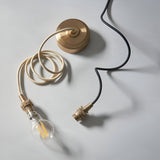 Endon Brackmont Flex Set in brushed brass with B22 lampholder, braided fabric cable, ceiling rose and filament bulb laid on a pale background.