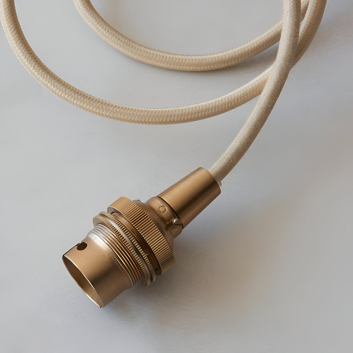 Endon Brackmont pendant flex set with brushed aged brass B22 lampholder and coiled natural braided fabric cable on a light background.