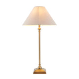 Caldmont Table Lamp with slim brass candlestick base and tapered natural linen shade, on a square stepped brass foot against a plain white background.