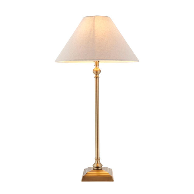 Caldmont Table Lamp with slim brass candlestick base and tapered natural linen shade, on a square stepped brass foot against a plain white background.
