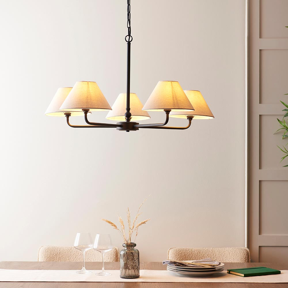 Endon Caldmere 5 Light Large Pendant in black with five tapered natural linen shades on a wide frame, hung above a dining table setting.