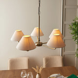 Caldmere 5 Light Large Pendant in brass with five tapered natural linen shades, hung on a chain above a dining table in a neutral room.
