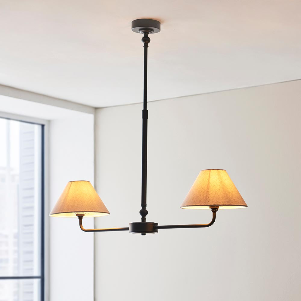 Endon Caldmere 2 Light Pendant in black with tapered natural linen shades on a linear bar and telescopic stem, mounted to a white ceiling.