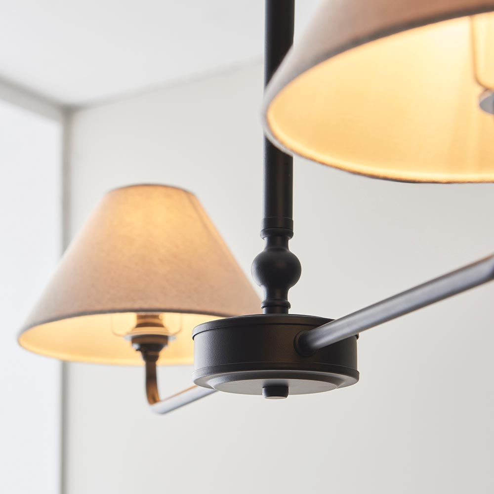 Close-up of Endon Caldmere 2 Light Pendant in Black and Natural, showing the matt black central fitting, telescopic stem detail, and tapered linen shades.