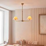 Caldmere 2-light pendant with tapered natural linen shades on a brass telescopic bar, shown above a dining table in a warm, panelled room.