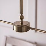 Close-up of the Caldmere 2 Light Pendant's antique brass ceiling mount and telescopic stem, showing the central bar joint against a light interior background.