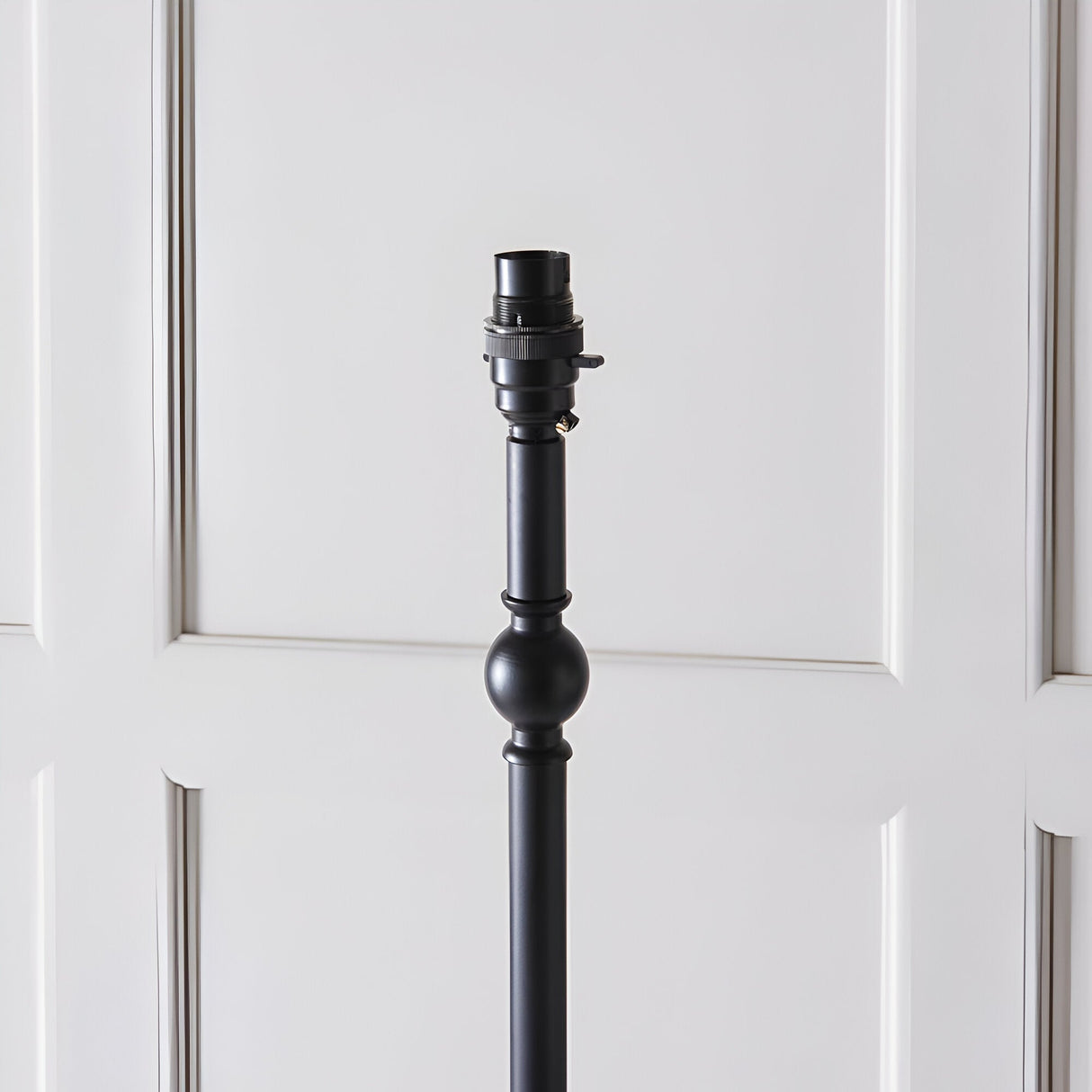 Caldmere Ikat Floor Lamp base in matt black metal with turned column and ball detail, B22 bulb holder shown against a light panelled background.